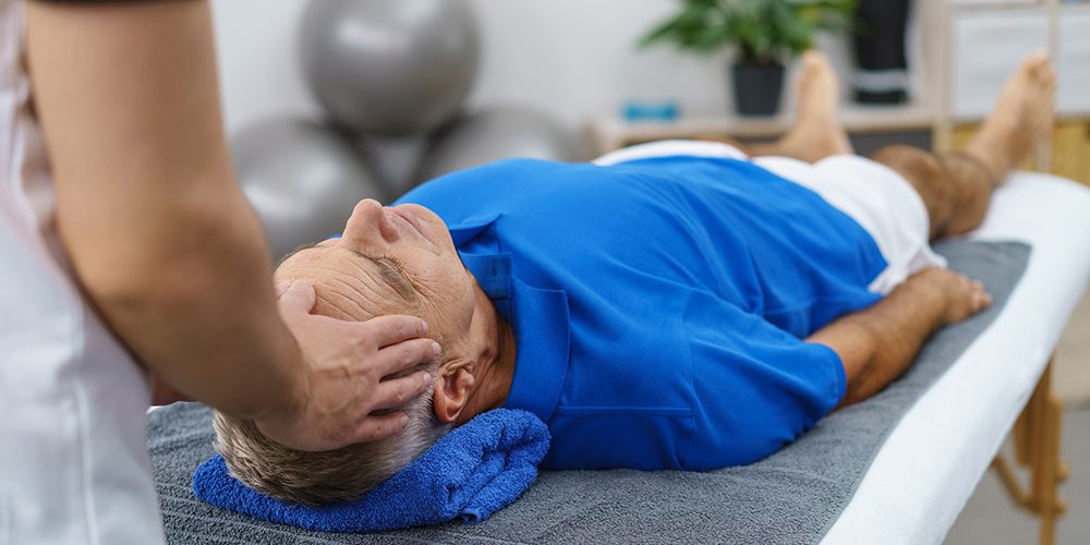 Person treating head of person laying on a treatment table