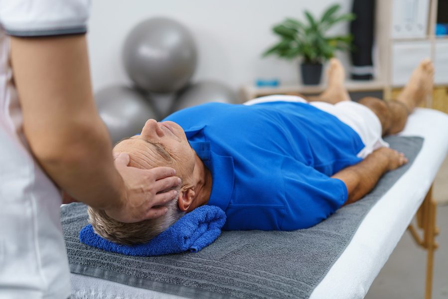 Person treating head of person laying on a treatment table