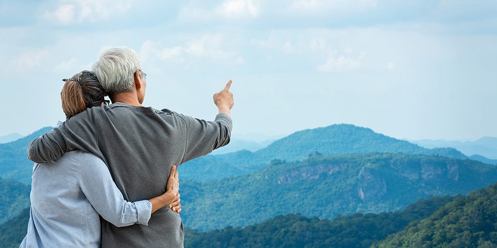 mature couple viewing beautiful mountains with arms around each other
