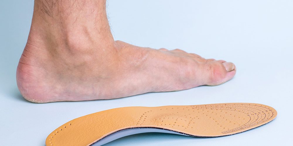 foot on the floor next to a foot orthotic